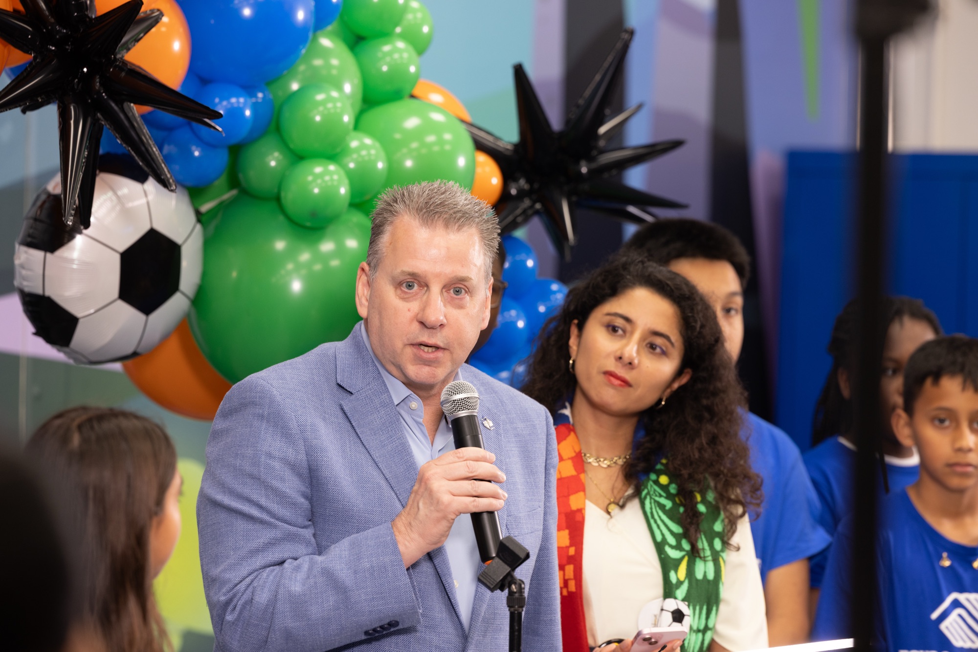 Speaker at a podium with soccer-themed balloon decorations at the Road to the World Cup youth ticket announcement